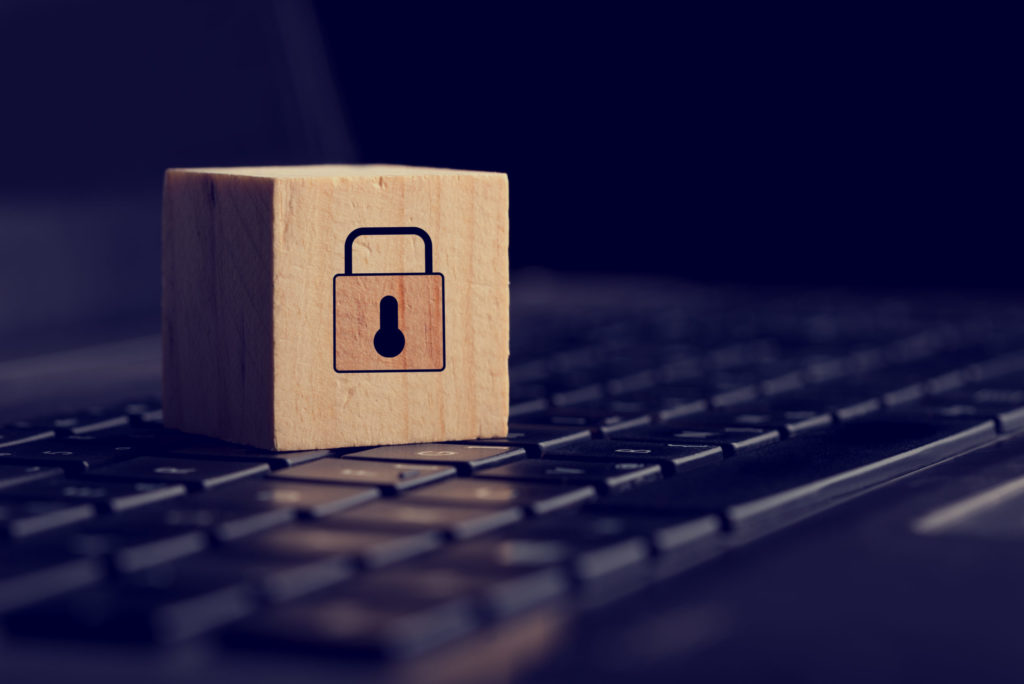 Holzwürfel mit Schloss-Symbol auf einer Laptop-Tastatur